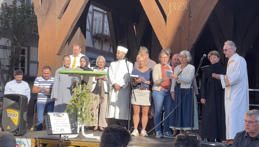 Mehrere Personen stehen auf einer Bühne und singen.