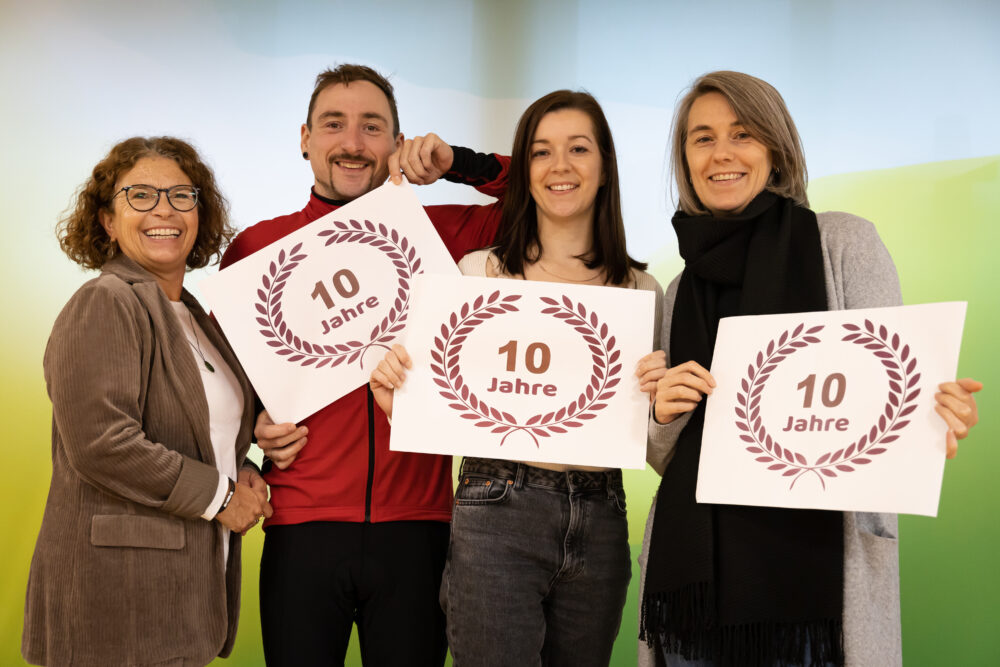 Drei Frauen und ein Mann halten ein 10 Jahre Schild